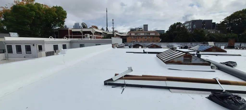 TPO-wrapped parapet and rusted gabled skylight frames contrasting with new white membrane at Grand Prix Motor Cars in Portland, OR